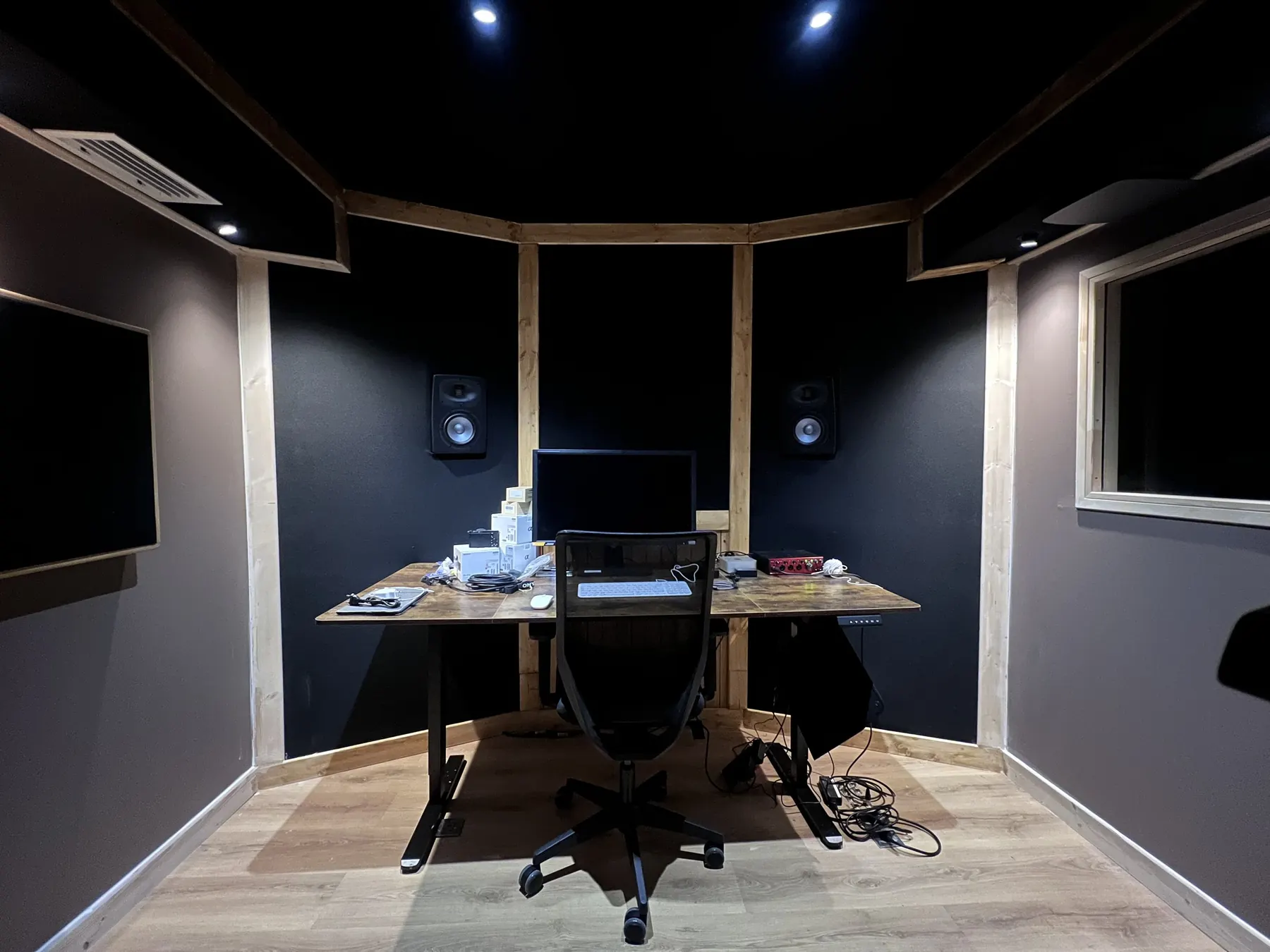 Control room livrée : parois non parallèles, panneaux absorbants, position de mixage centrée.